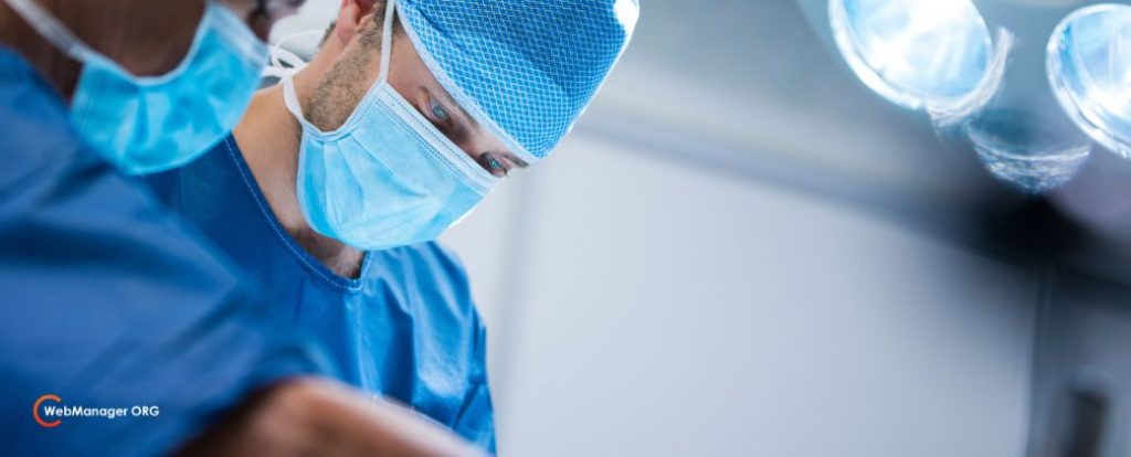 נקודת חן סרטנית - ניתן לראות אנשי צוות רפואי מבצעים הליך כירורגי ובצד שמאל למטה לוגו אתר blog.webmanager